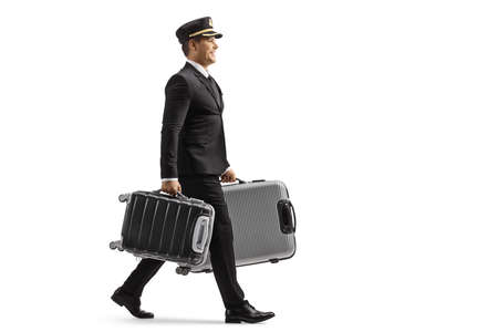 Full length profile shot of a porter in a uniform walking and carrying suitcases isolated on white backgroundの写真素材