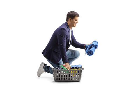Man with a laundry basket kneeling and sorting clothesの写真素材
