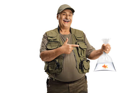 Happy mature fisherman holding a golden fish in a plastic bag and pointing isolated on white...