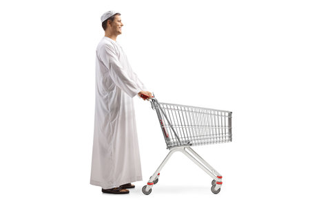 Full length profile shot of a man in ethnic clothes with an empty shopping trolley isolated on white backgroundの写真素材