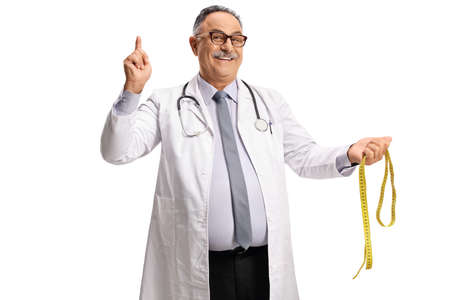 Mature male doctor holding a measuring tape and pointing up isolated on white background