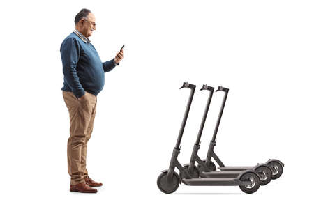 Full length profile shot of an elderly man with a mobile phone and electric scooters isolated on white backgroundの写真素材