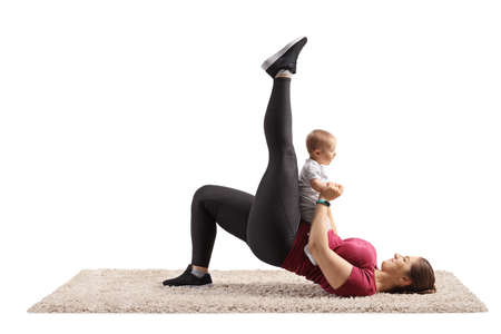 Mother lying on a carpet and exercising with her baby isolated on white backgroundの写真素材