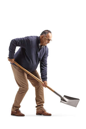 Mature man in casual clothes digging with a shovel isolated on white backgroundの写真素材