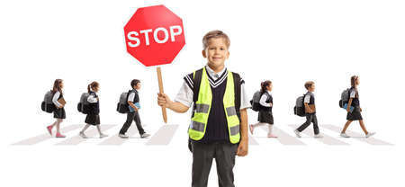 Schoolboy in a reflective safety vest holding a stop sign and children crossing a street isolated on white backgroundの写真素材