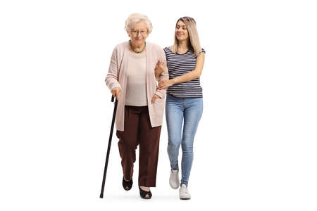 Full length portrait of a kind young woman helping an elderly woman walking with a cane isolated on white backgroundの写真素材