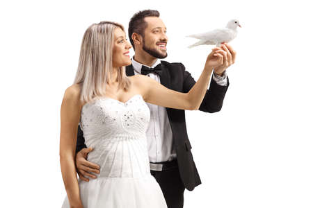Profile shot of bride and groom holding a white dove isolated on white backgroundの写真素材