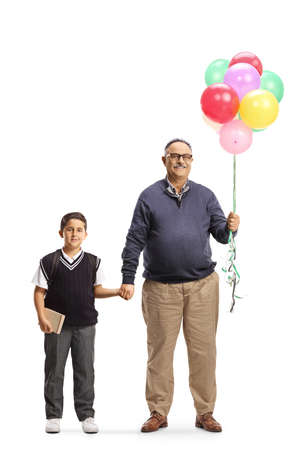 Full length portrait of a schoolboy with his grandfather holding balloons and smiling isolated on white backgroundの写真素材