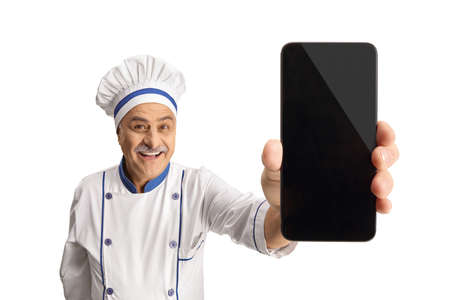 Mature male chef holding a smartphone isolated on white backgroundの写真素材