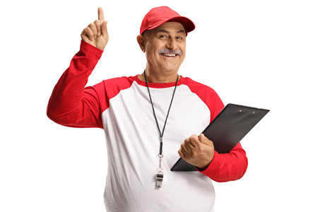 Mature baseball coach with a wistle and a clipboard pointing up isolated on white background