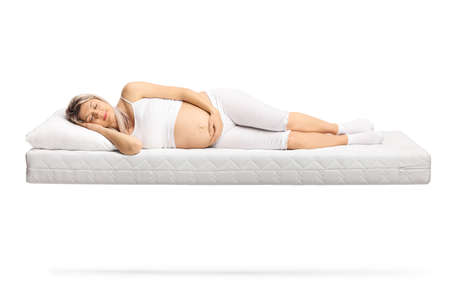 Pregnant woman in pajamas sleeping on a floating mattress isolated on white backgroundの写真素材