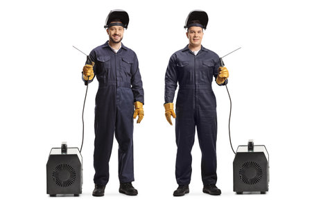 Full length portrait of two welders with welding machines isolated on white background