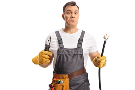 Portrait of a confused electrician holding a cable and pliers isolated on white backgroundの写真素材