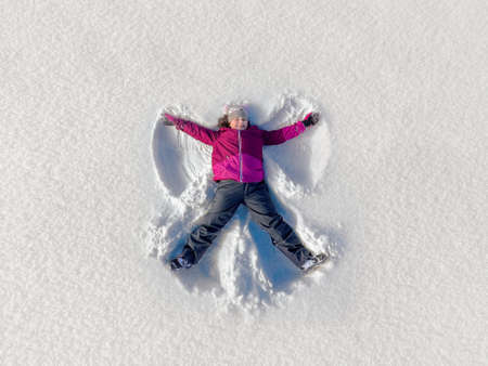 Girl making angels in the snowの写真素材
