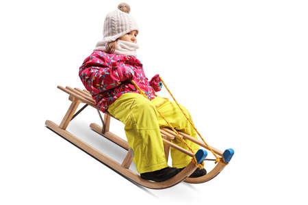 Little girl sliding on a wooden sleigh isolated on white backgroundの写真素材