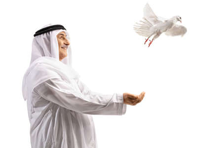 Arab in ethnic clothes smiling and letting a white dove fly isolated on white backgroundの素材 [FY310182772711]