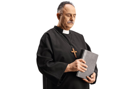 Mature priest holding a bible and looking down isolated on white backgroundの写真素材