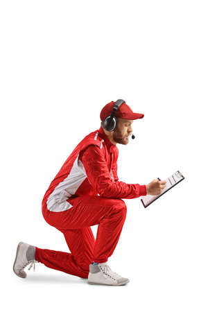 Member of a racing team kneeling and writing on a clipboard isolated on white backgroundの写真素材