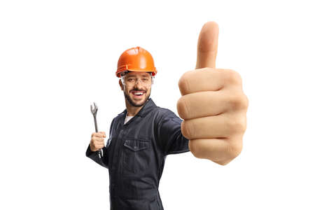 Worker in a uniform with helmet holding showing a thumb up gesture isolated on white backgroundの写真素材