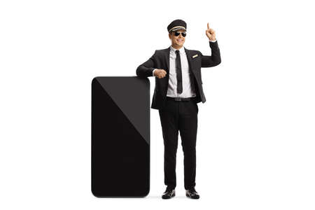 Chauffeur leaning on a big mobile phone and pointing up isolated on white backgroundの写真素材