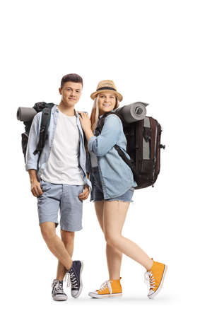 Full length portrait of a young male and female backpackers smiling at camera isolated on white backgroundの写真素材