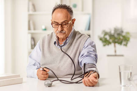 Mature man measuring blood pressure at home