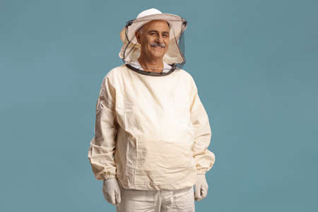 Mature male bee keeper in a uniform isolated on blue backgroundの写真素材