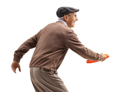 Profile shot of an elderly man playing a game with throwing a plastic disk isolated on white backgroundの写真素材