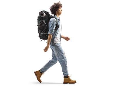 Full length profile of a young male traveler walking with a backpack isolated on white background