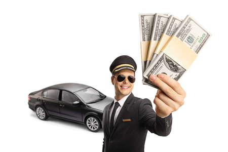 Professional chauffeur holding money in front of a black car isolated on white background
