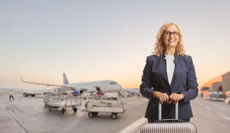 Businesswoman with a suitcase posing on an airportの写真素材