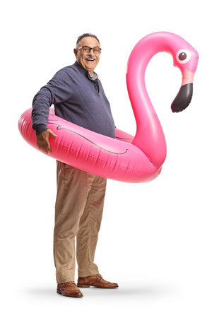 Mature man with a big inflatable flamingo rubber ring isolated on white backgroundの写真素材