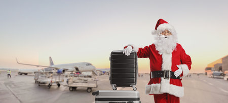 Santa claus standing on an airport apron and leaning on suitcasesの写真素材