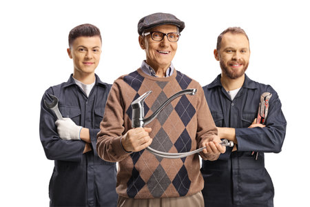 Elderly man holding a plastic water pipe and plumbers standing behind isolated on white backgroundの写真素材