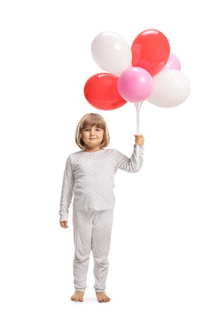 Cute little girl in pajamas holding balloons isolated on white backgroundの写真素材