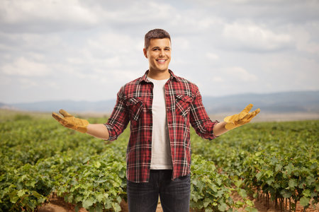 Happy young farmer with gloves posing on a grape vine fieldの写真素材