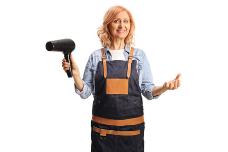 Female hair stylist wearing an apron and holding a hair dryer isolated on white backgroundの写真素材