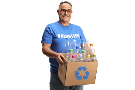 Cheerful mature man volunteer holding a box with plastic bottles for recycling isolated on white backgroundの写真素材