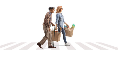 Woman crossing street and carrying grocery bags  for an elderly man isolated on white backgroundの写真素材