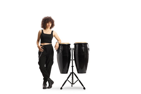 Full length portrait of a young female leaning on conga drums isolated on white background