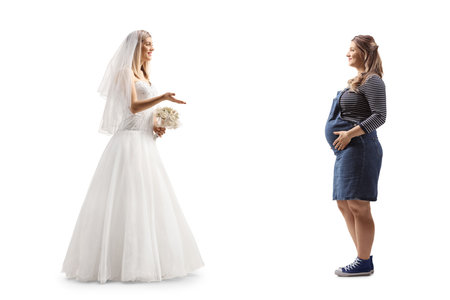 Full length profile shot of a bride talking to a pregnant woman isolated on white backgroundの写真素材