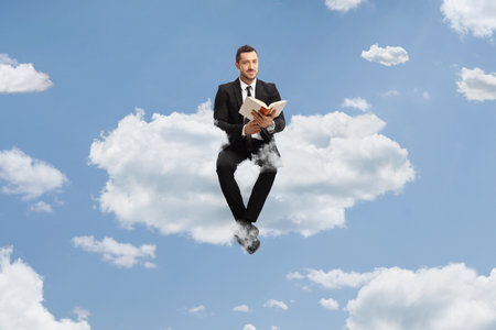 Businessman sitting on a cloud with a book in his hands
