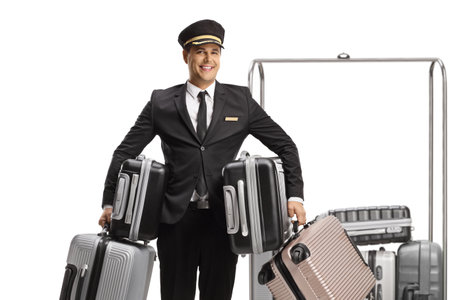 Bellboy holding many suitcases and standing in front of a luggage cart isolated on white backgroundの写真素材