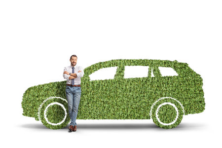 Full length portrait of a man leaning on a green car made of grass isolated on white backgroundの写真素材