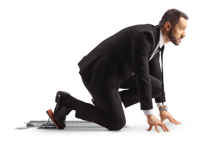 Full length profile shot of a businessman preparing for a run on starting blocks isolated on white backgroundの写真素材