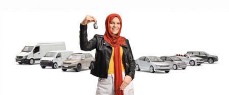 Young muslim woman with a hijab holding car keys and smiling in front of parked vehicles isolated on white backgroundの写真素材