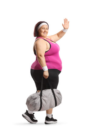 Side shot of an overweight woman with a sports bag walking and waving isolated on white backgroundの写真素材
