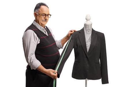 Tailor measuring a suit sleeve on a mannequin doll isolated on white backgroundの写真素材