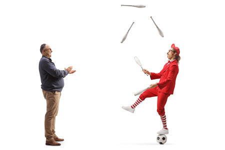 Full length profile shot of a mature man giving an applause and watching a guy juggling isolated on white backgroundの写真素材