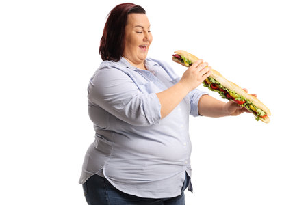 Happy corpulent woman in eating a big baguette sandwich isolated on white backgroundの写真素材